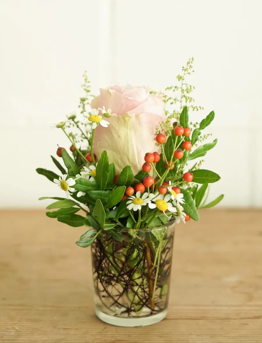 Rose mit Beeren und Kamille im Glas
